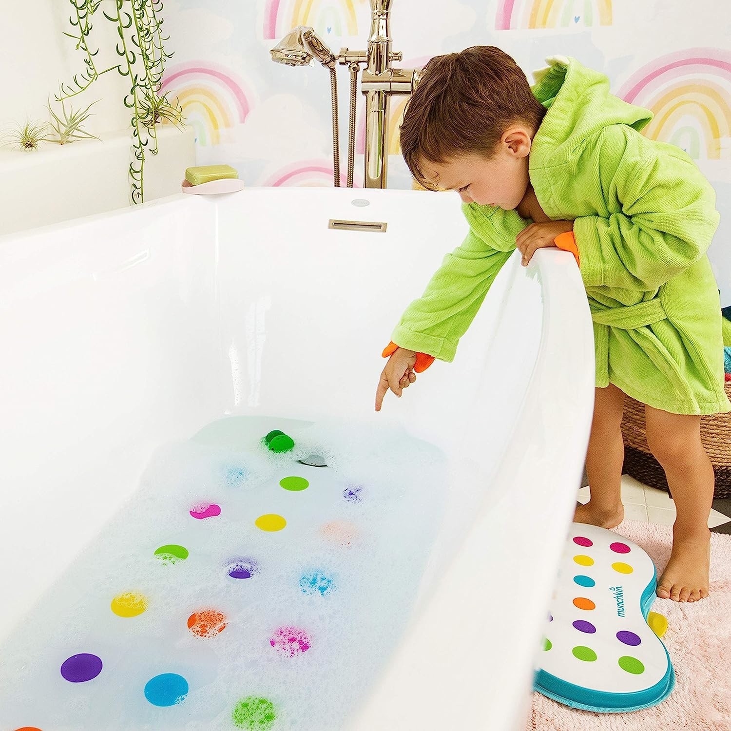 child reaching into bathtub to point at mat under the water