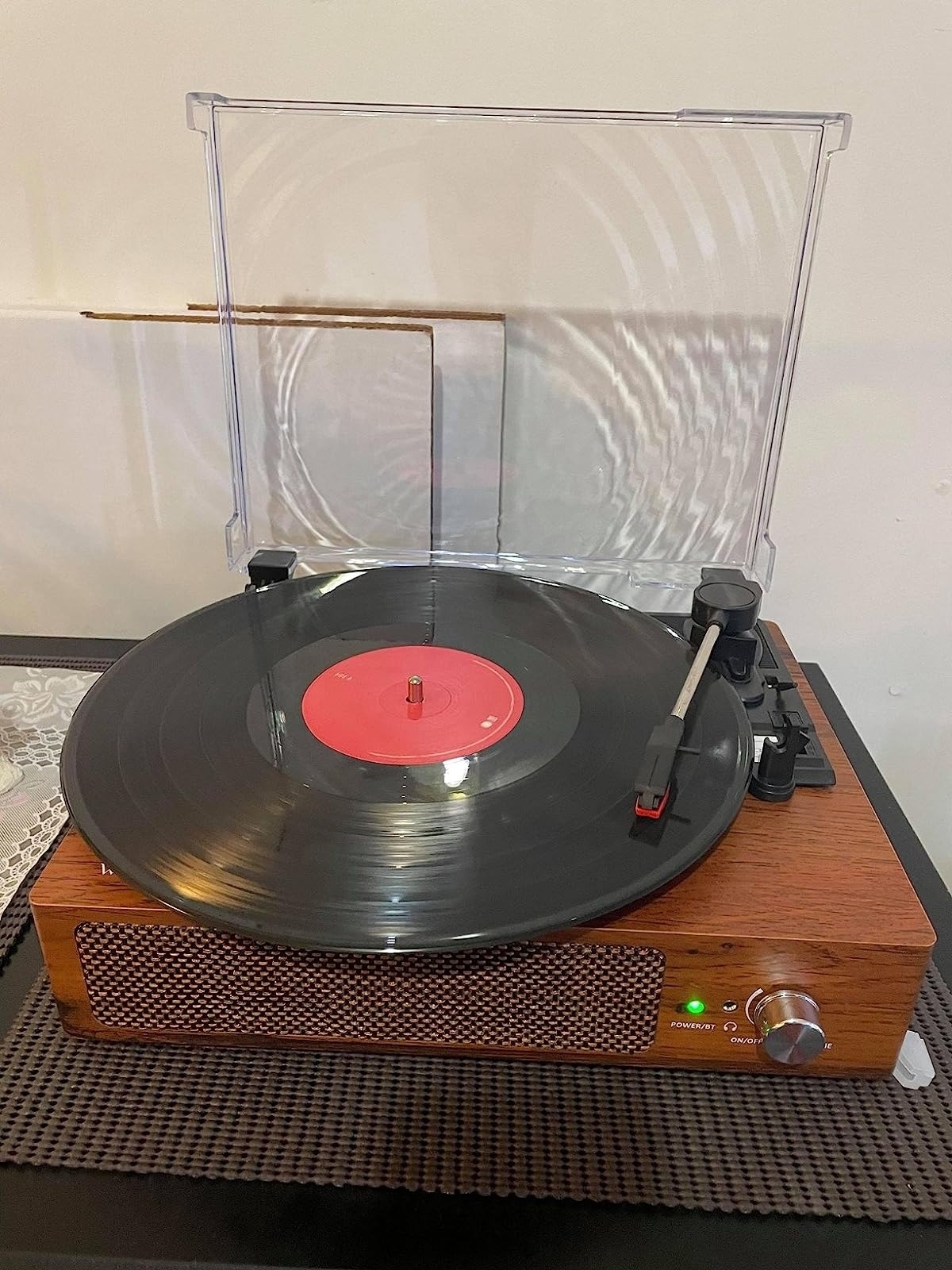 reviewer showing a vinyl record player with a black vinyl playing in it