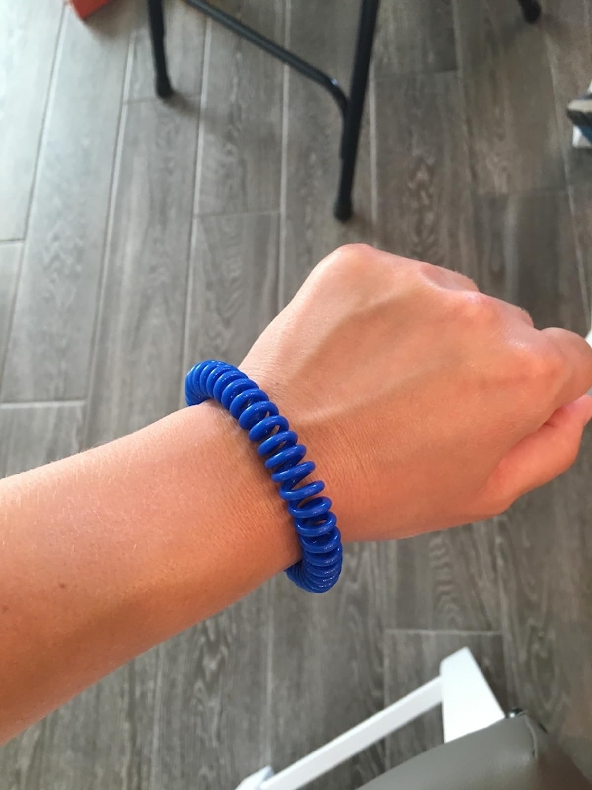 image of reviewer wearing a blue mosquito-repellant bracelet on their wrist