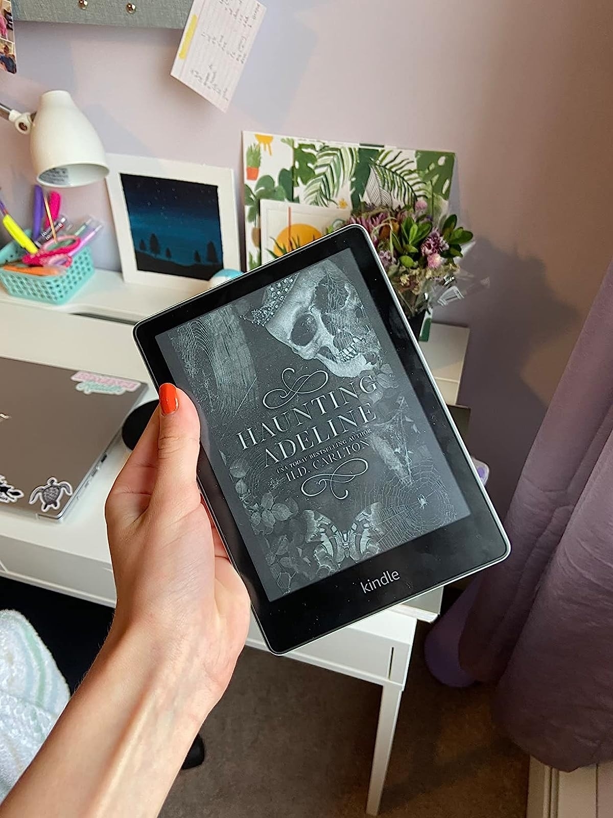 a reviewer holding up their Kindle showing the cover of haunting Adeline