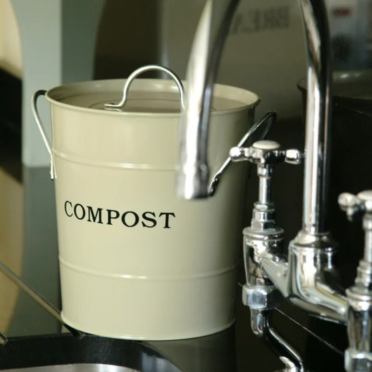 the ivory compost bin on a counter next to a sink