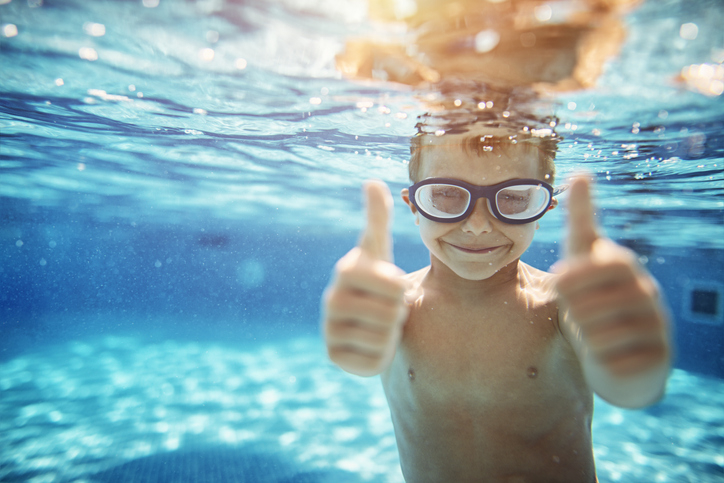 kid underwater giving two thumbs up