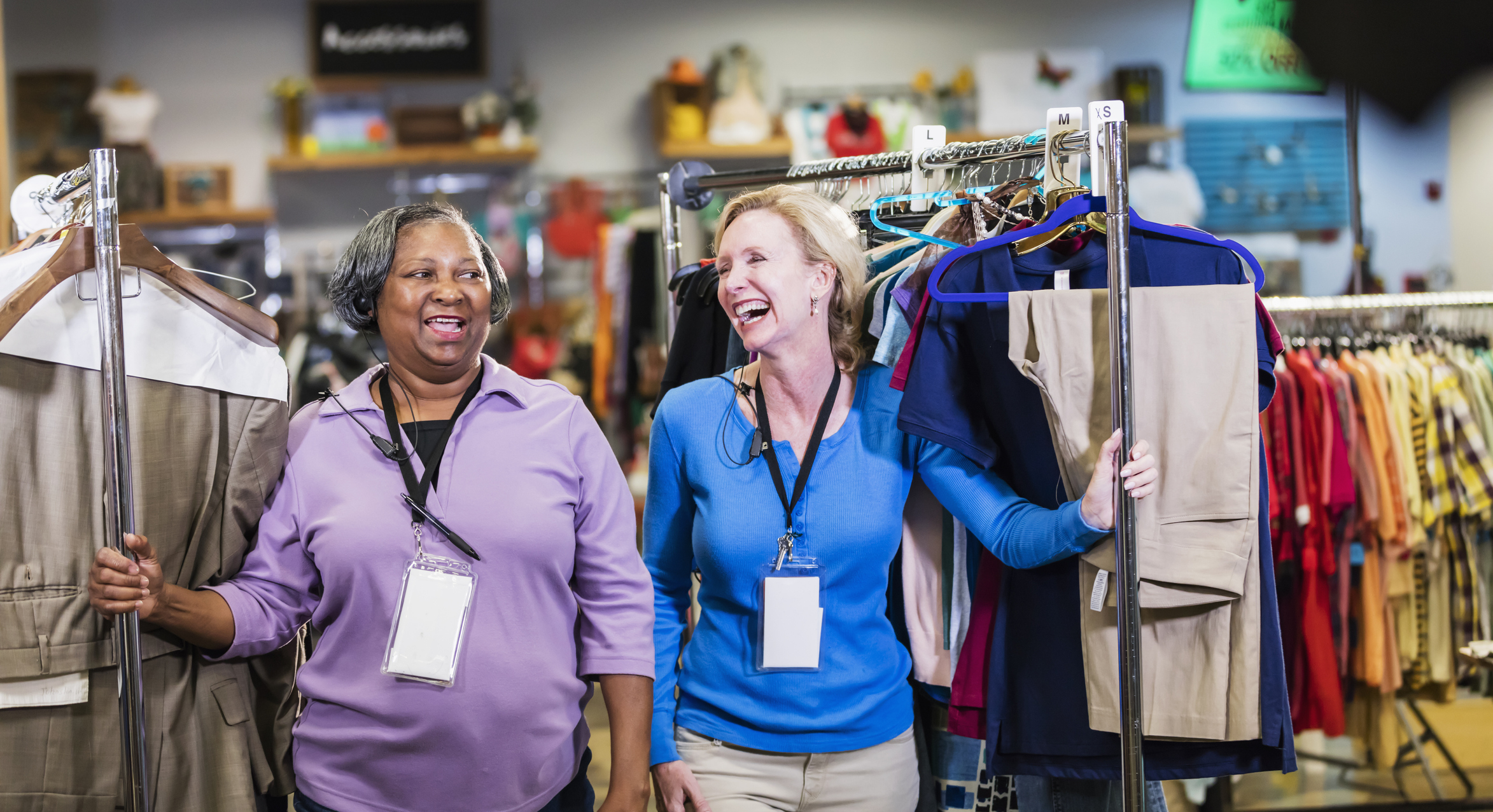 woman laughing at they roll out racks of clothes