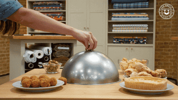 A GIF of a cloche being removed from the table, revealing a man popping his head up