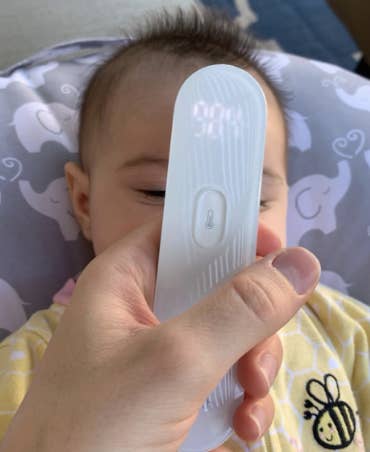 reviewer using thermometer on baby
