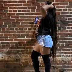side view of reviewer wearing the denim shorts with thigh-high boots and a tee