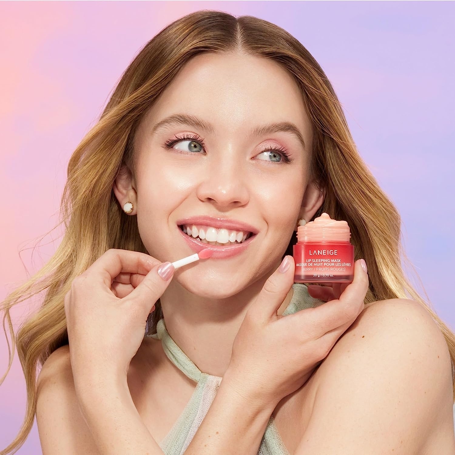 a model holding the container and putting some of the mask on their lips