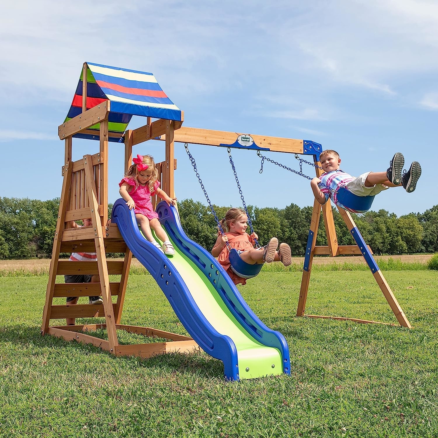four children playing on a wooden swing set, which has a slide and two swings