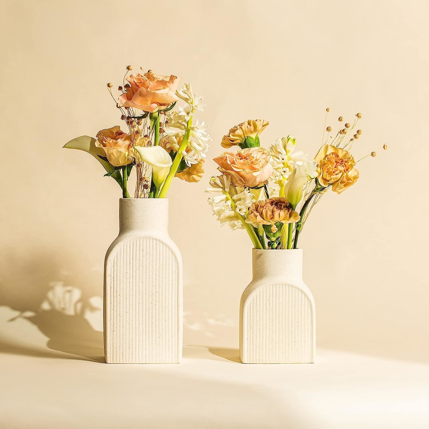 two vases of different sizes holding flowers