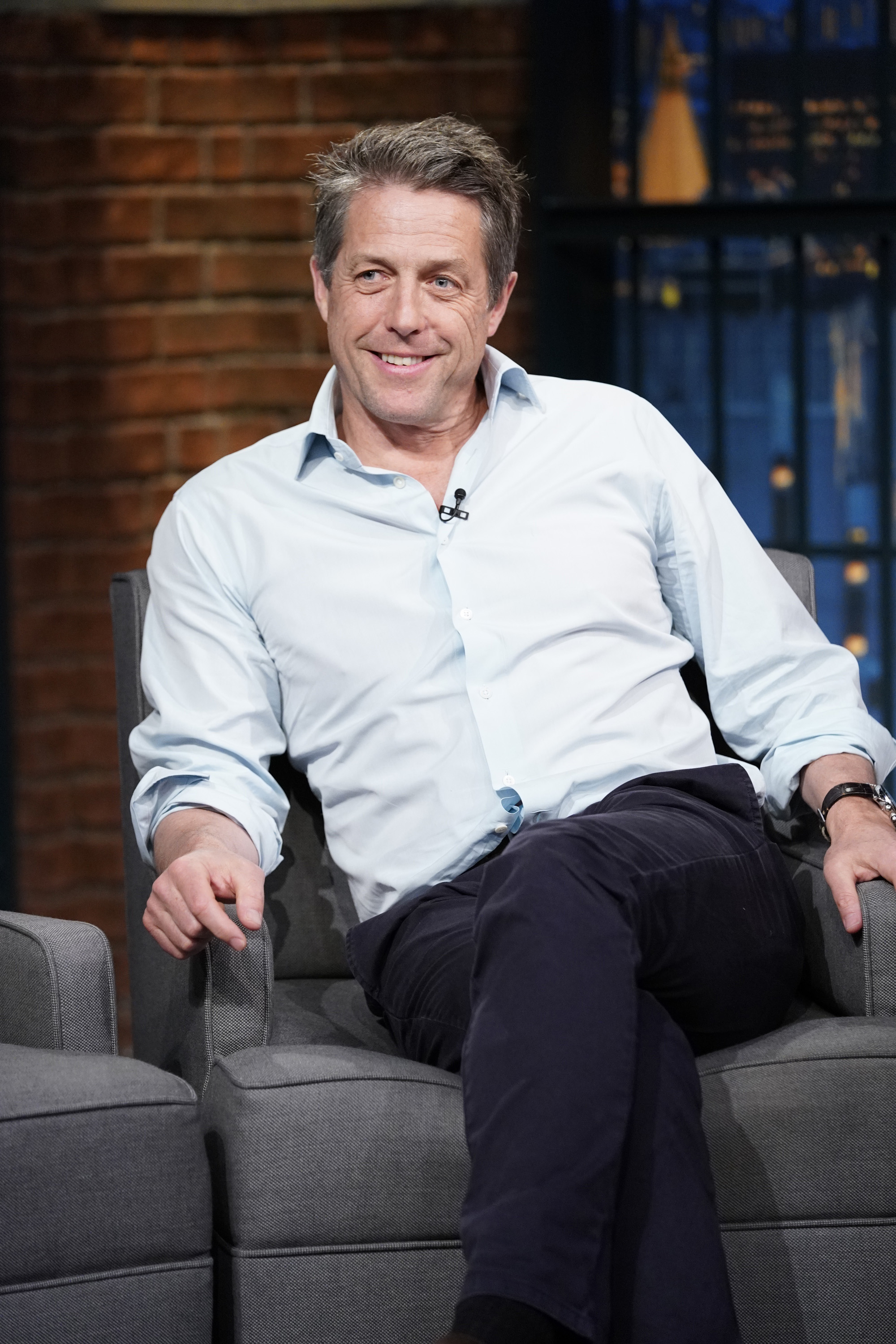 Hugh Grant sitting on a talk show couch