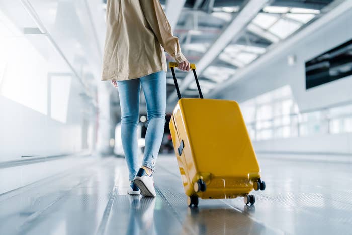 a person dragging a yellow suitcase