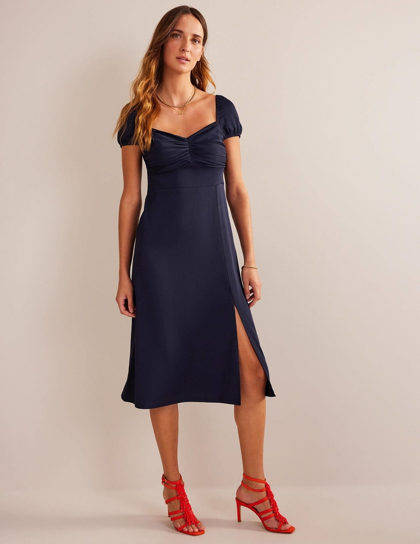 A model wearing a blue dress with a leg slit.
