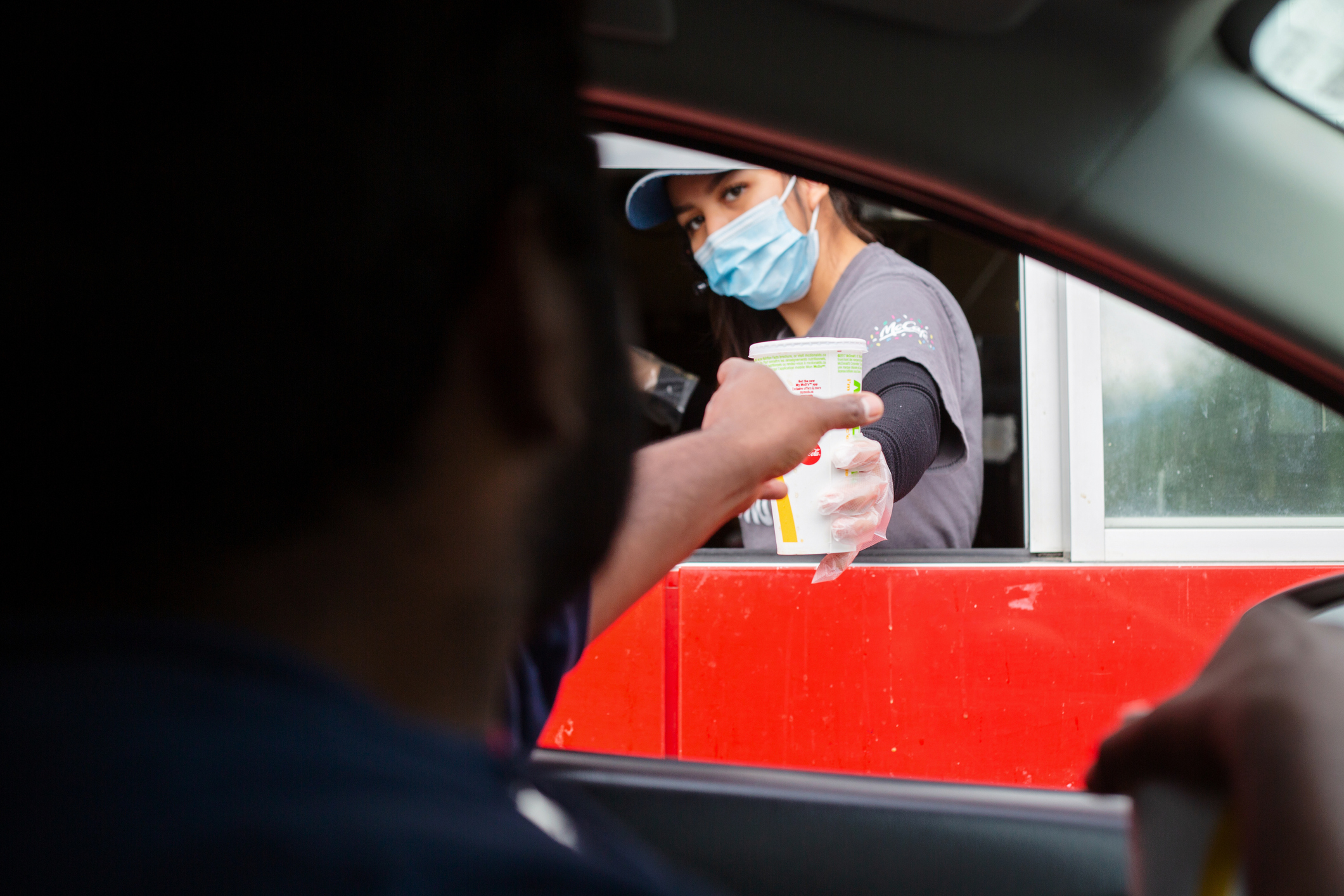 McDonald&#x27;s employee handing customer a drink in the drive-thru