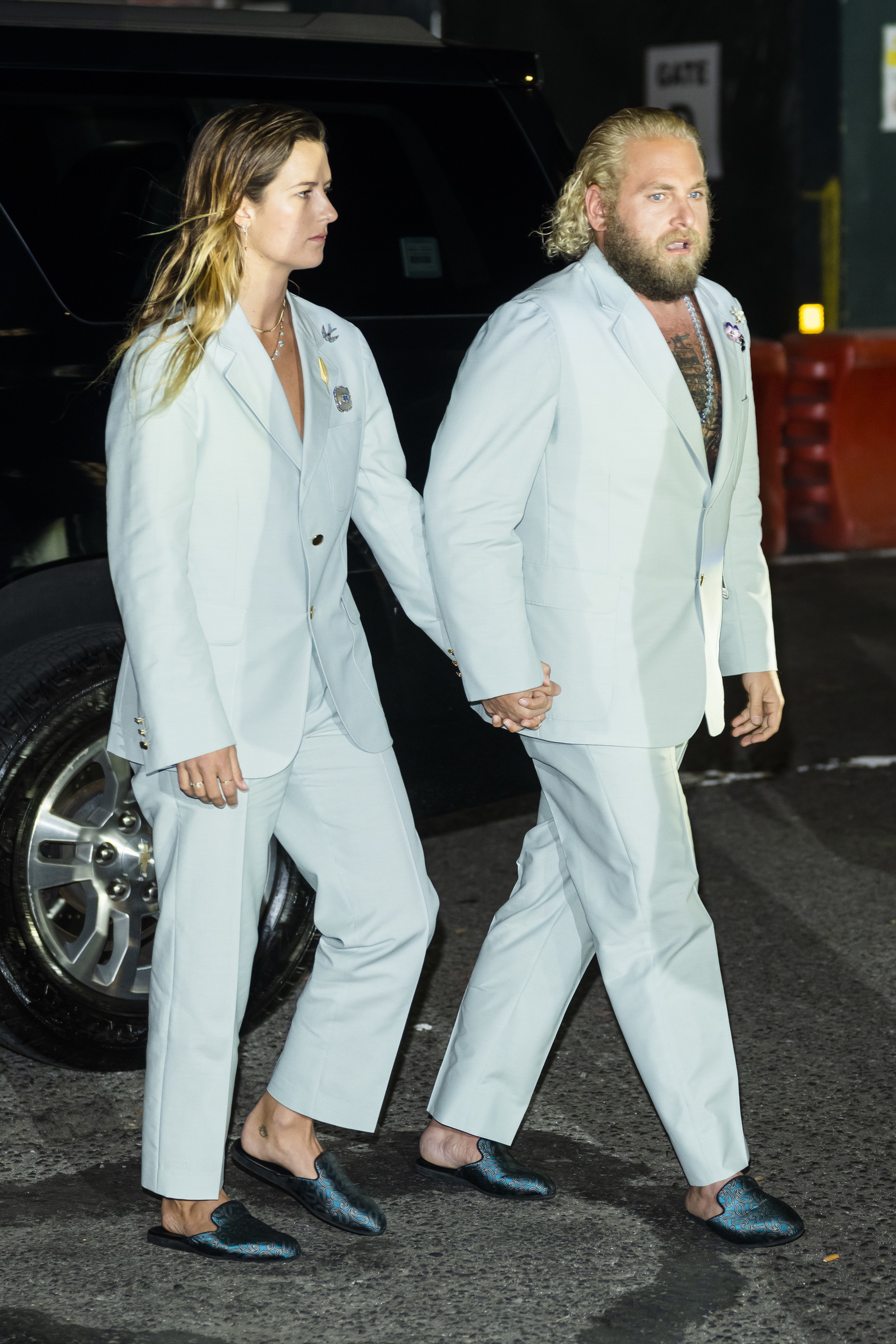 The couple walking to an event wearing matching pantsuits and slip-on looafers