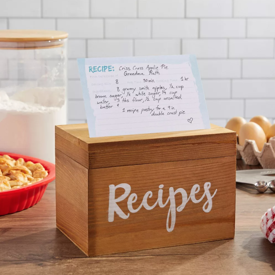 a small wooden recipe box with the word &quot;recipes&quot; painted on it, with a recipe card on top of it on a kitchen countertop