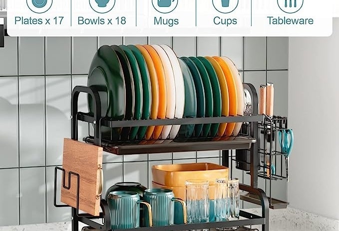 The dish rack filled with drying plates, cups, and utensils