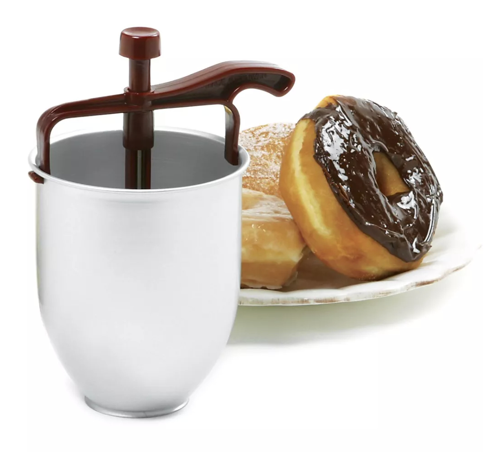 a batter dispenser and a plate of donuts