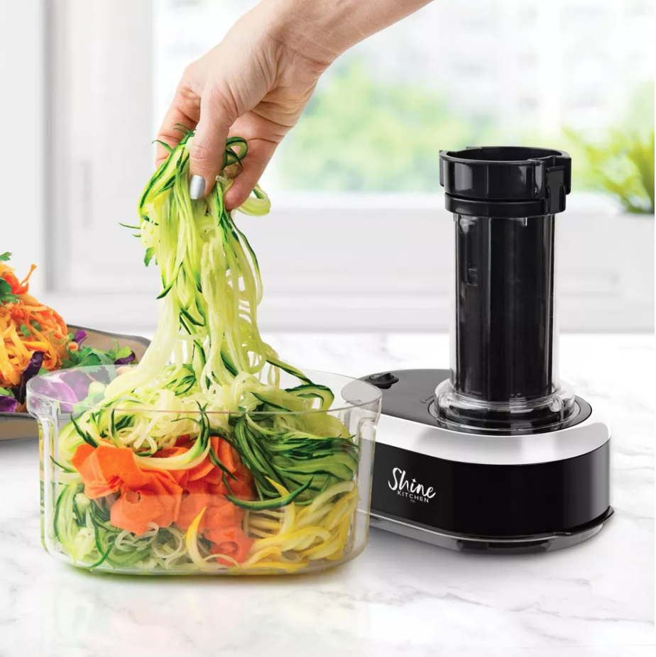 a person pulling spiralized vegetables out of a container next to the spiralizer
