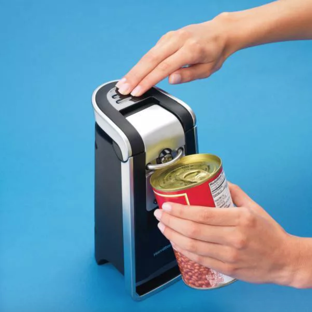 a person using an electric can opener to open a can of beans