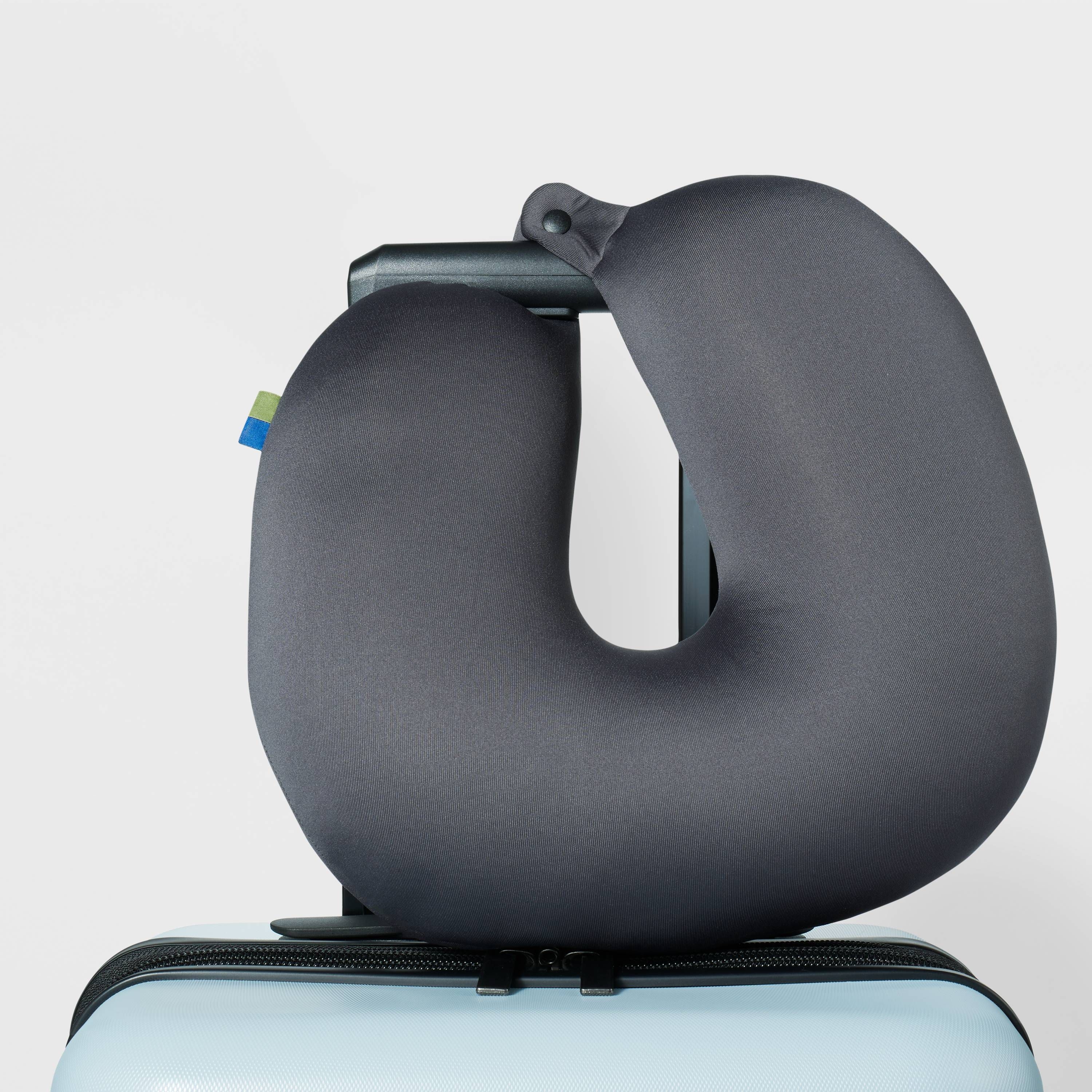 grey neck pillow looped on a roller suitcase handle