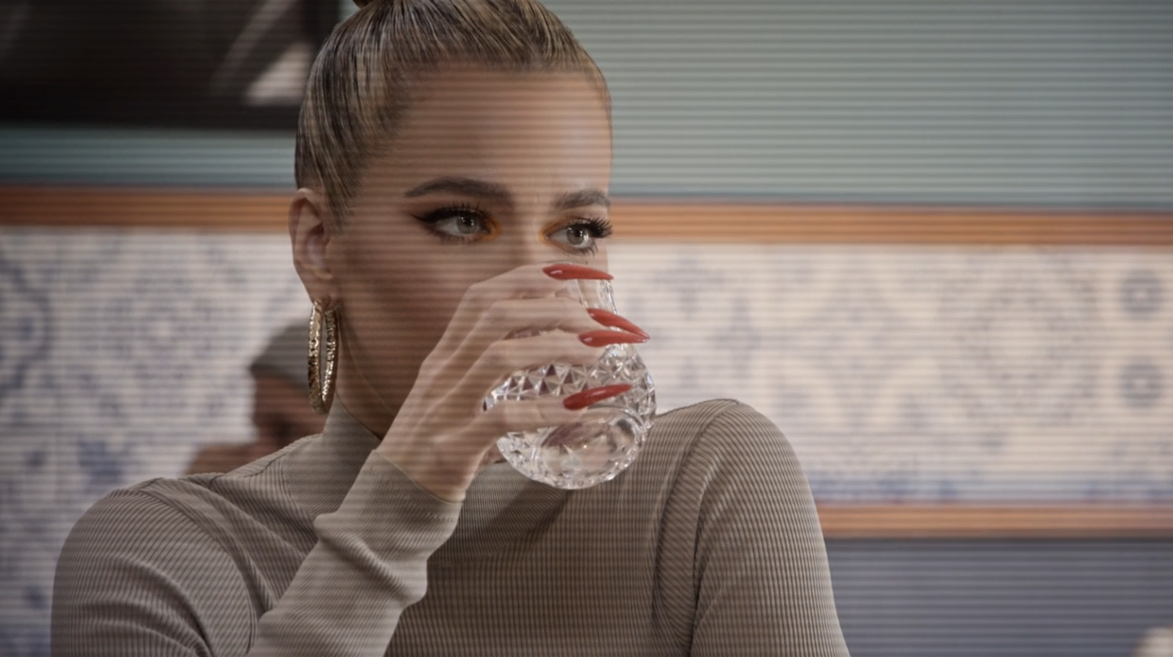A closeup of Khloé holding a glass up to her mouth