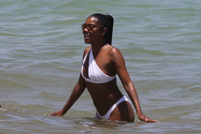 Gabrielle standing in the ocean while wearing a bikini and sunglasses