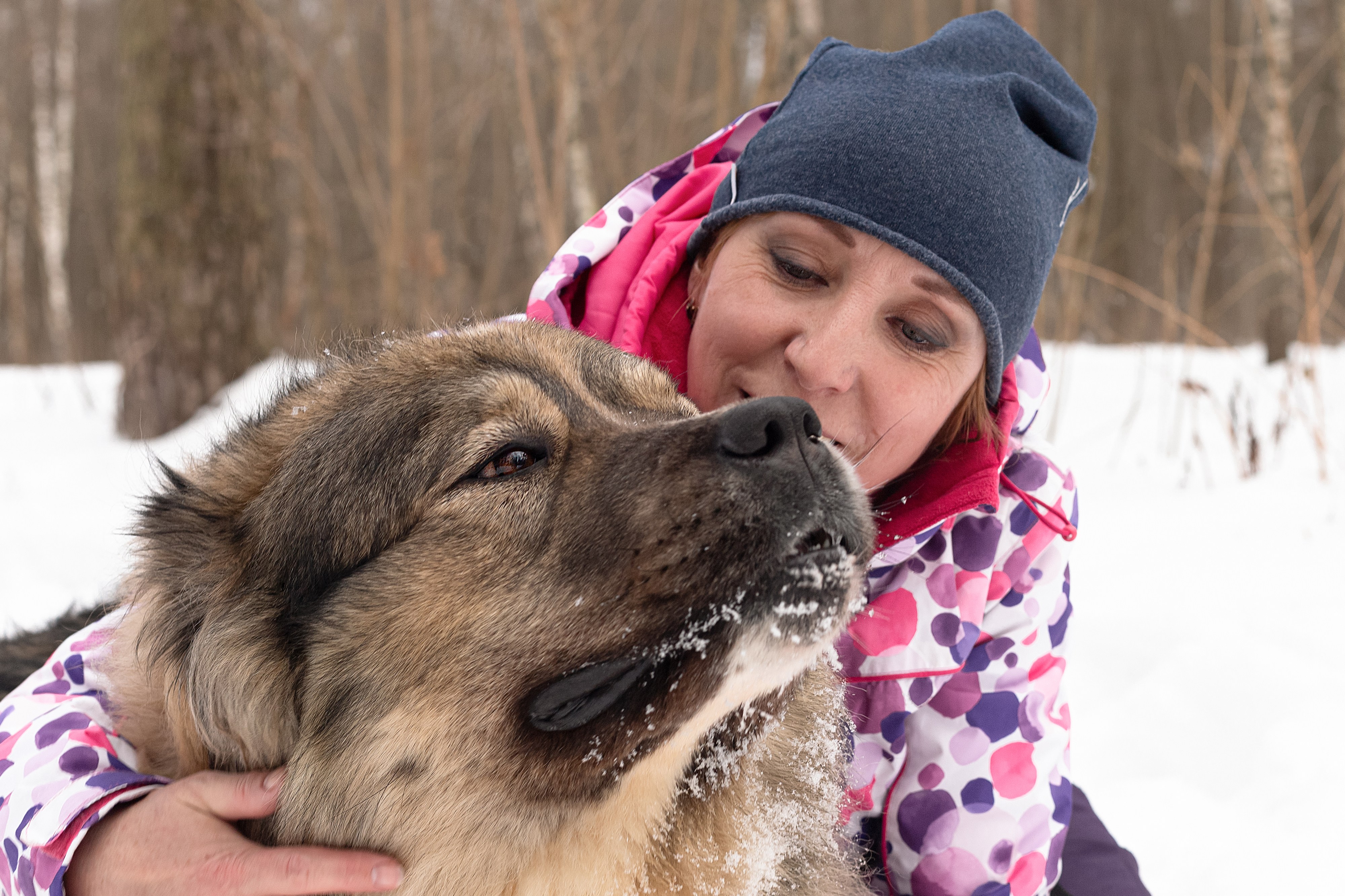 A woman with her arm around a big fluffy dog.