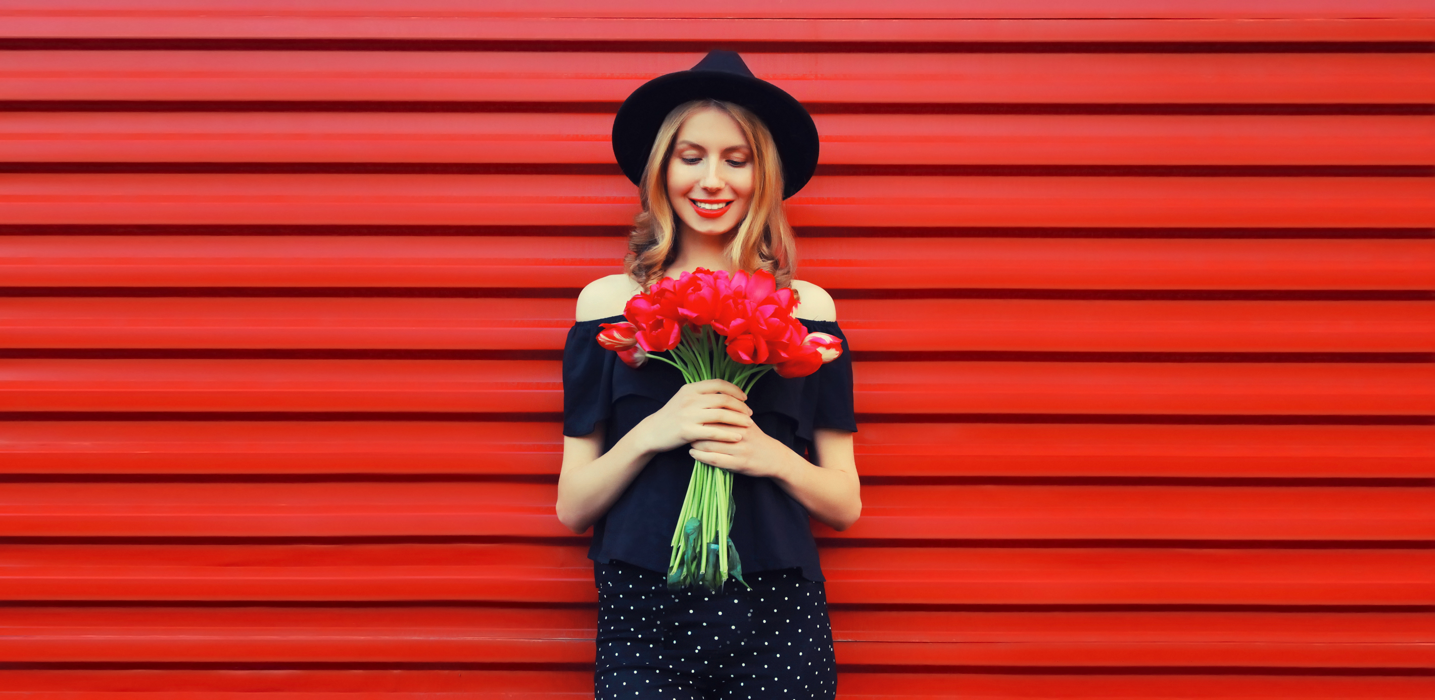 A woman wearing black and holding a bunch of red roses