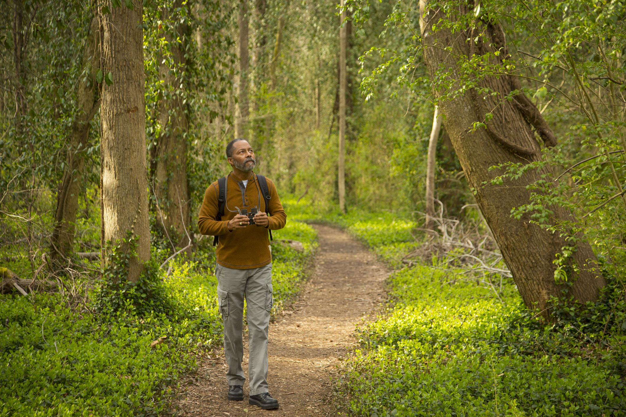 a black man walking on a trail in the woods