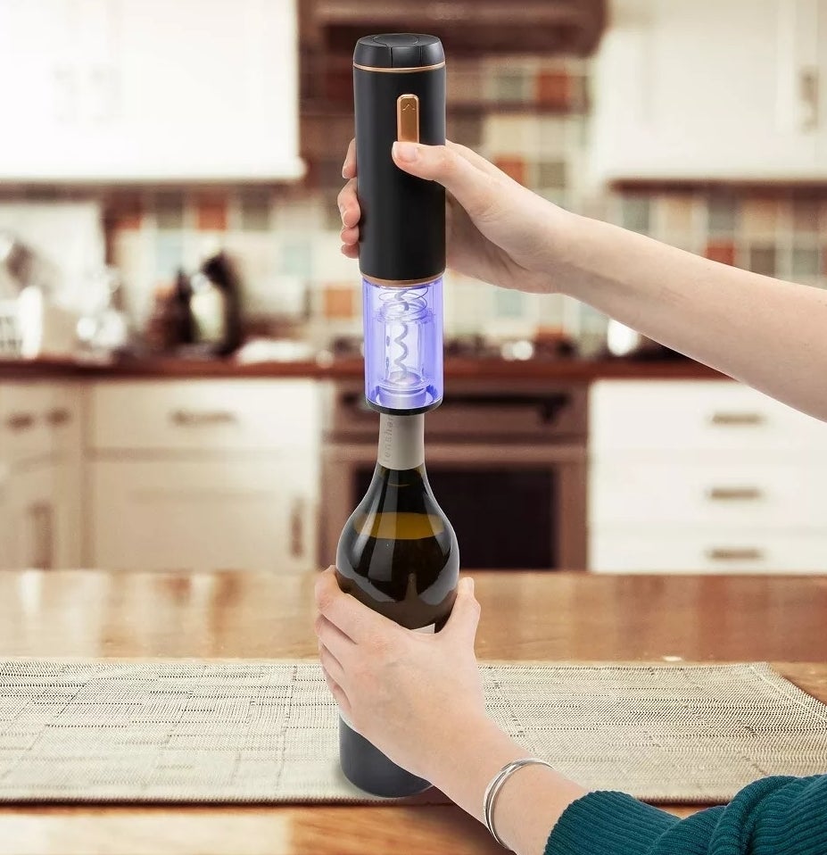 model using electric wine opener on a wine bottle