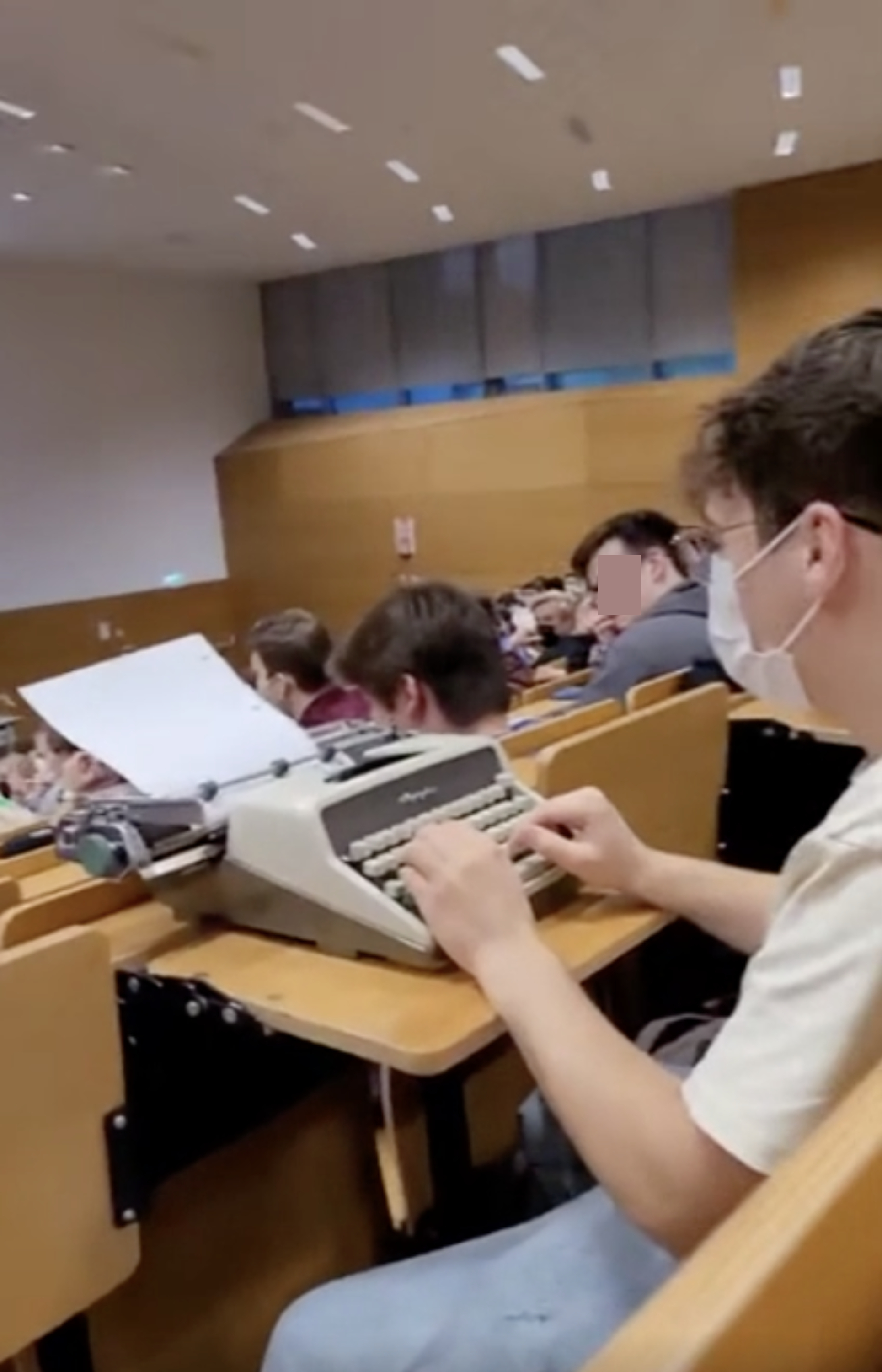 Student sitting in class typing on a typewriter