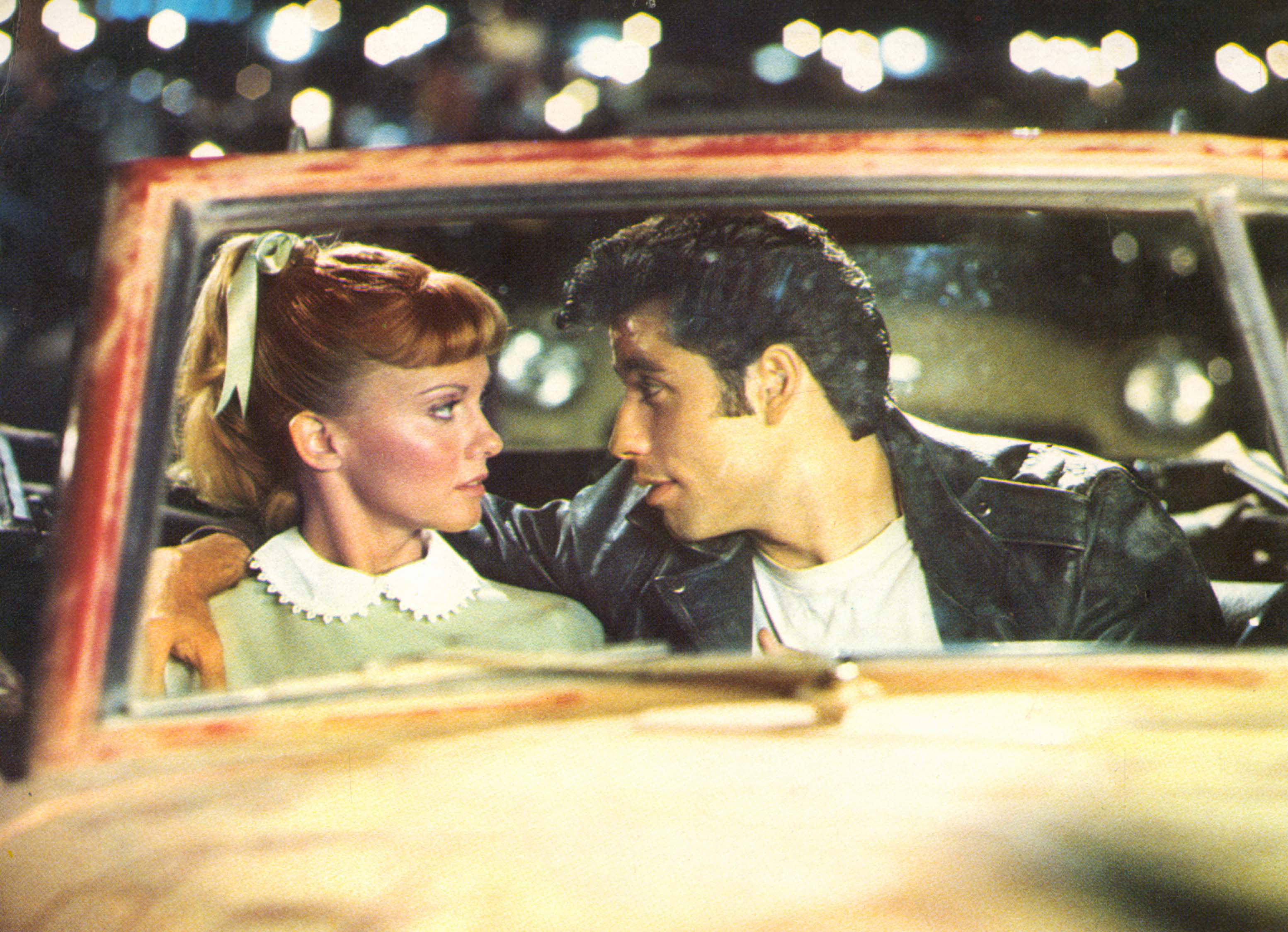 Olivia Newton-John and John Travolta sitting in a car in Grease