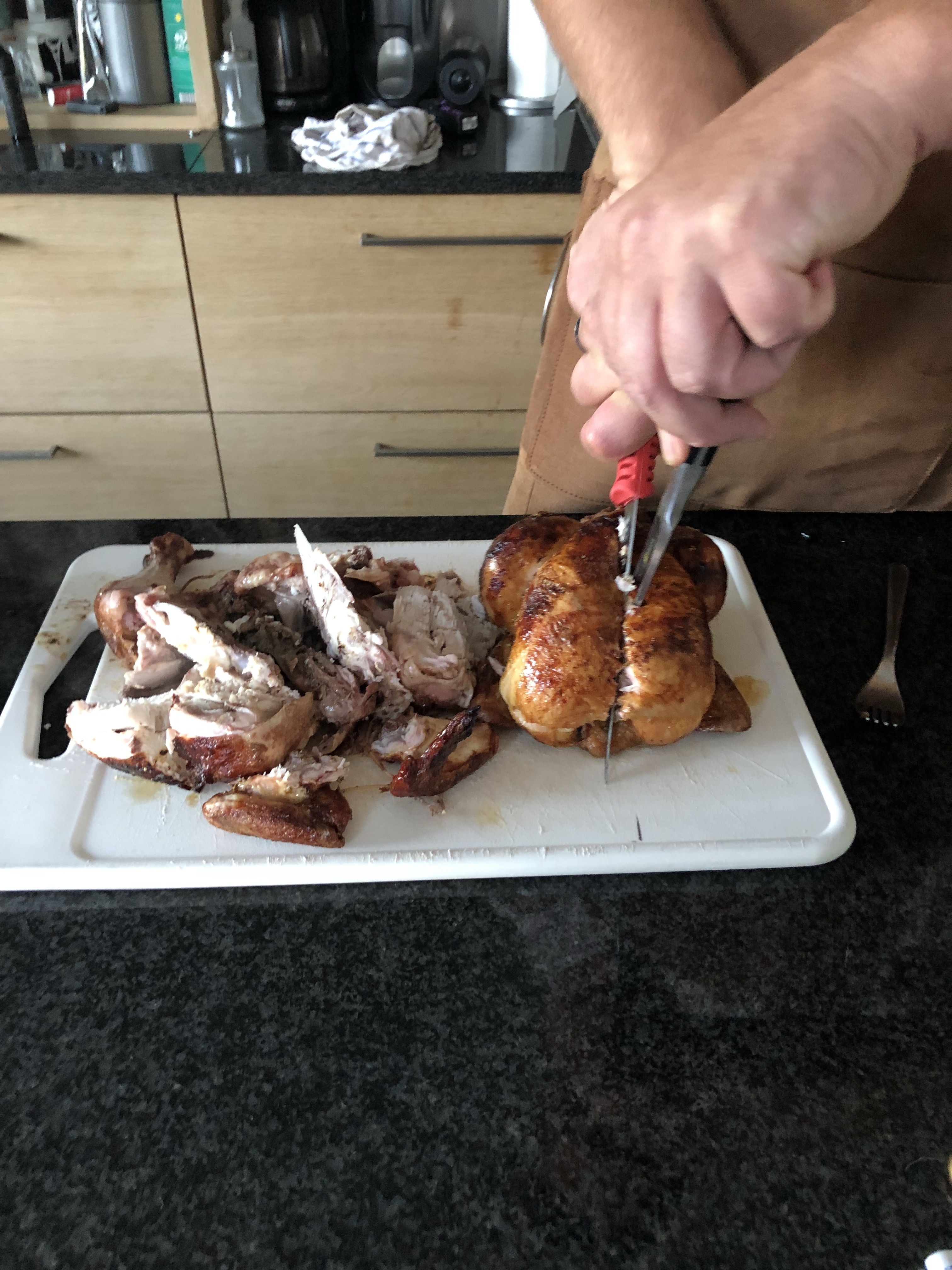 slicing up a rotisserie chicken on a cutting board