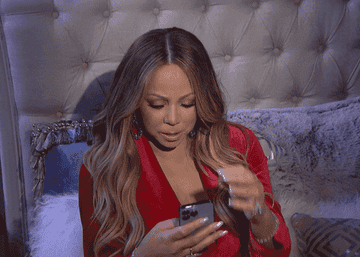 Mariah Carey scrolling through her phone and touching her hair