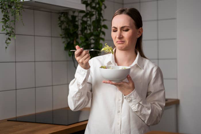 A woman making a stank face while holding a fork of food in front of her face