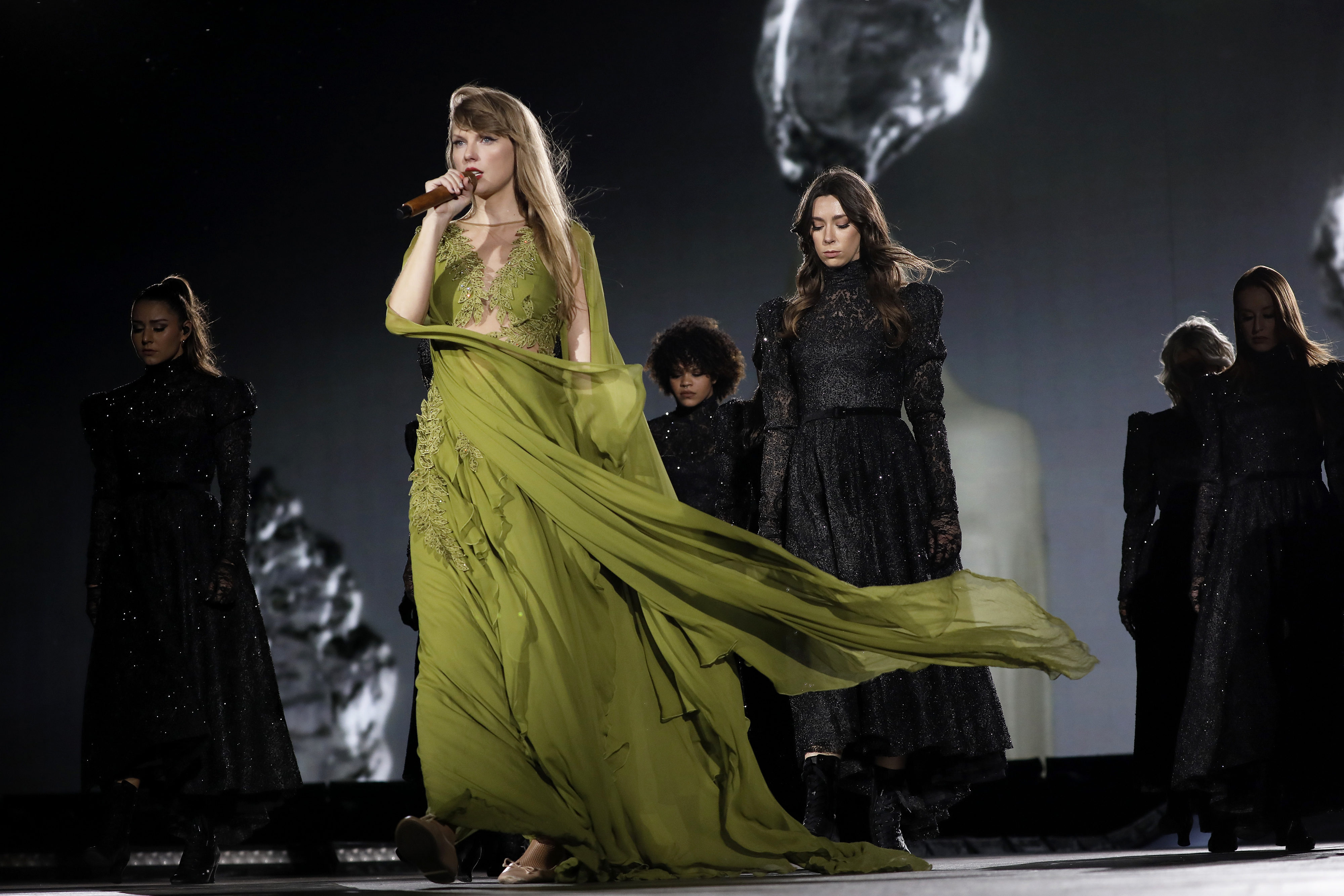 Taylor Swift performing in a green dress during The Eras Tour