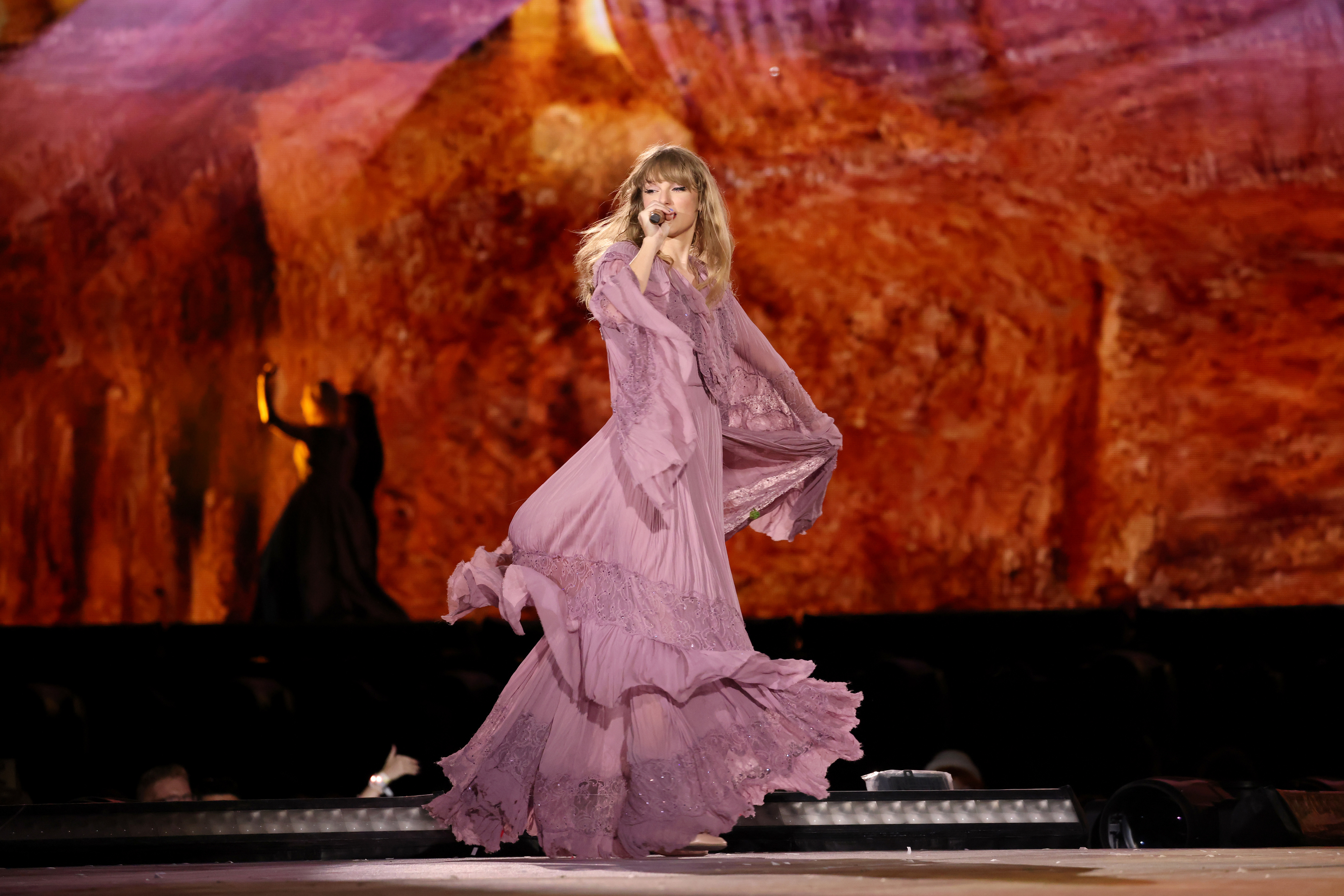 Taylor Swift dancing in a violet-purple dress during The Eras Tour