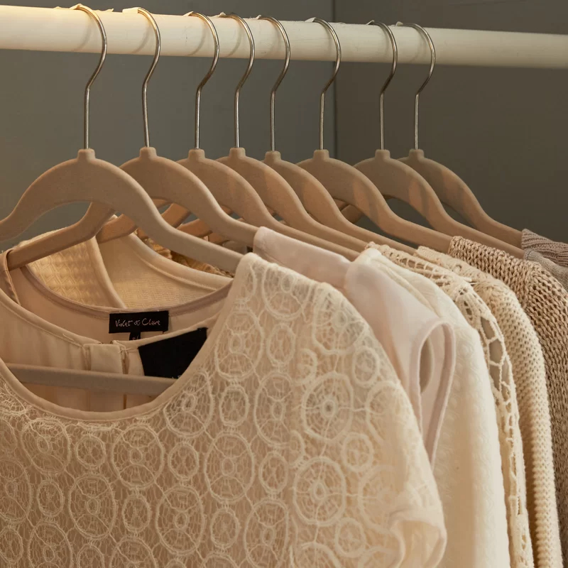 clothes hanging on the hangers in tan in a closet