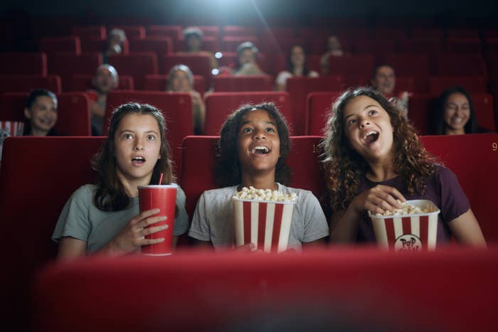 Group of surprised friends watching a movie in cinema