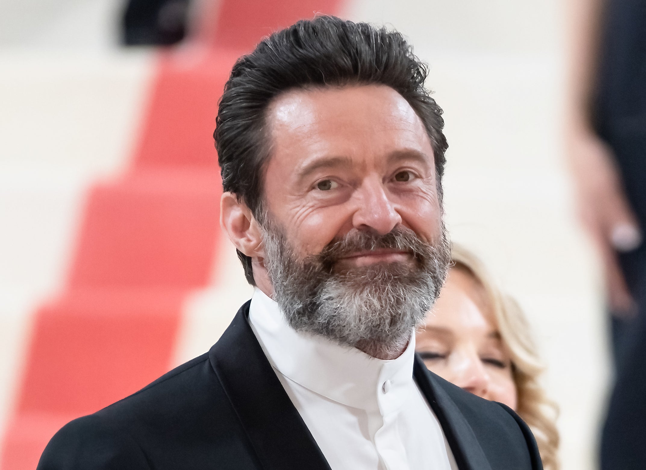 Hugh Jackman smiling as he attends a red carpet event