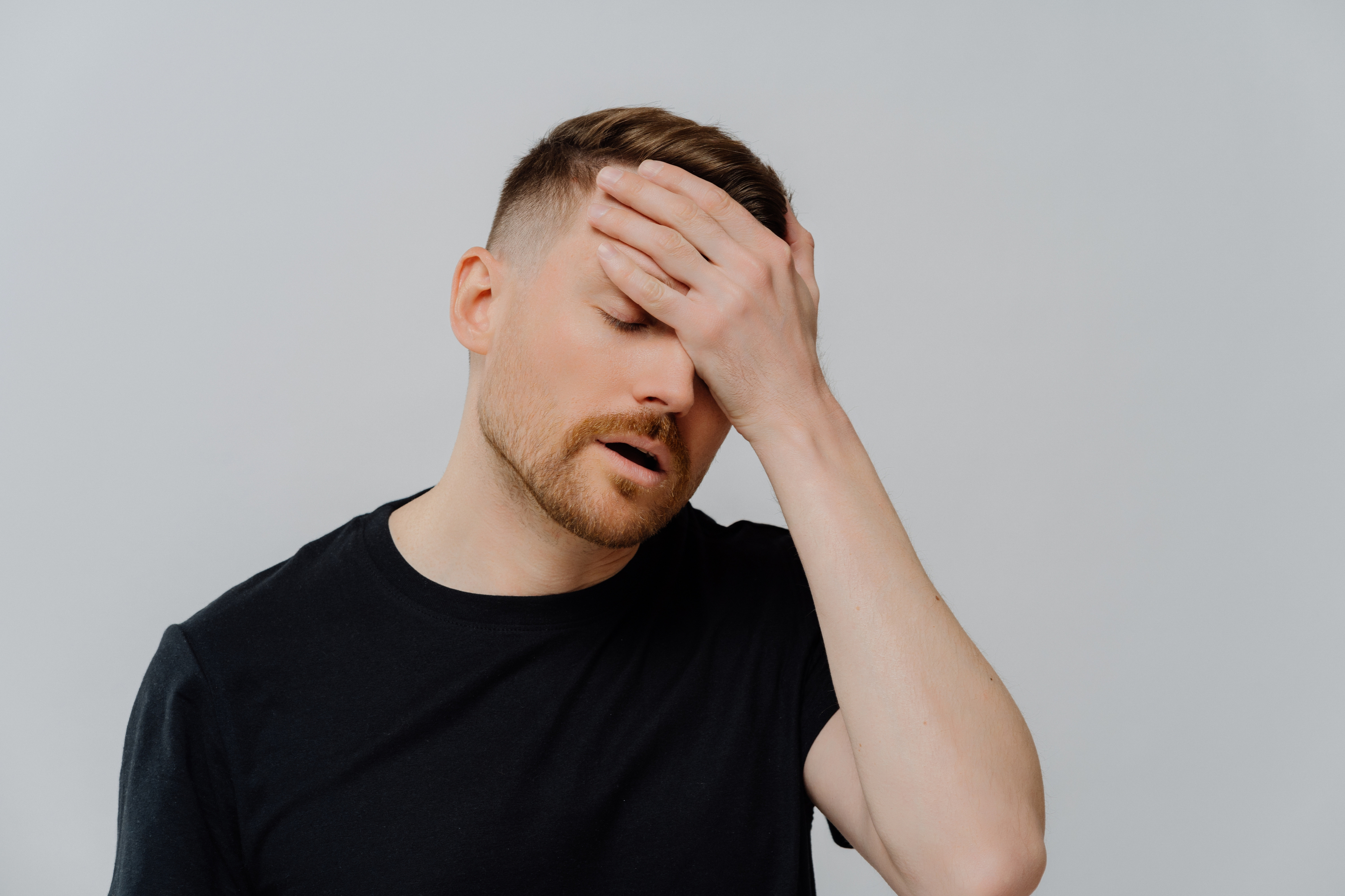A man with his hand on his forehead and eyes closed