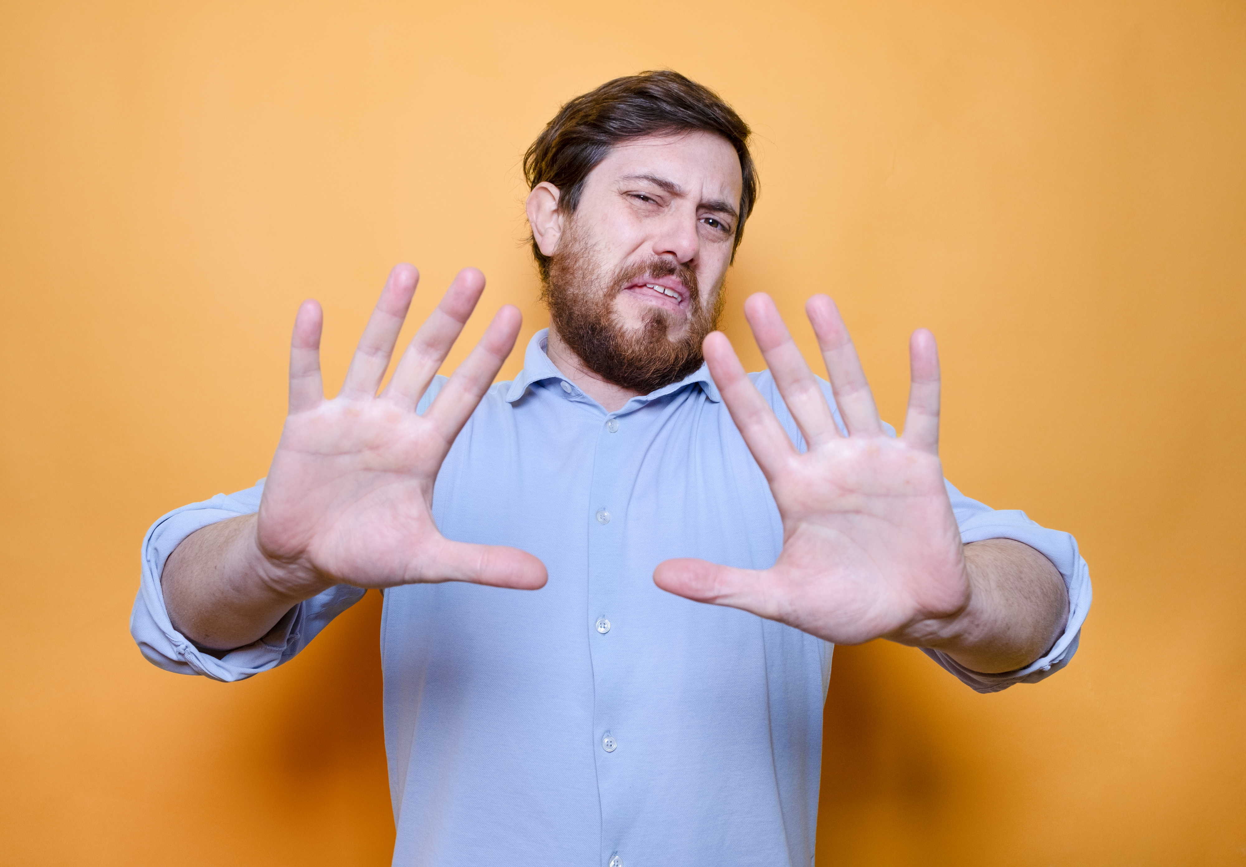A man with a cringey face and his hands up