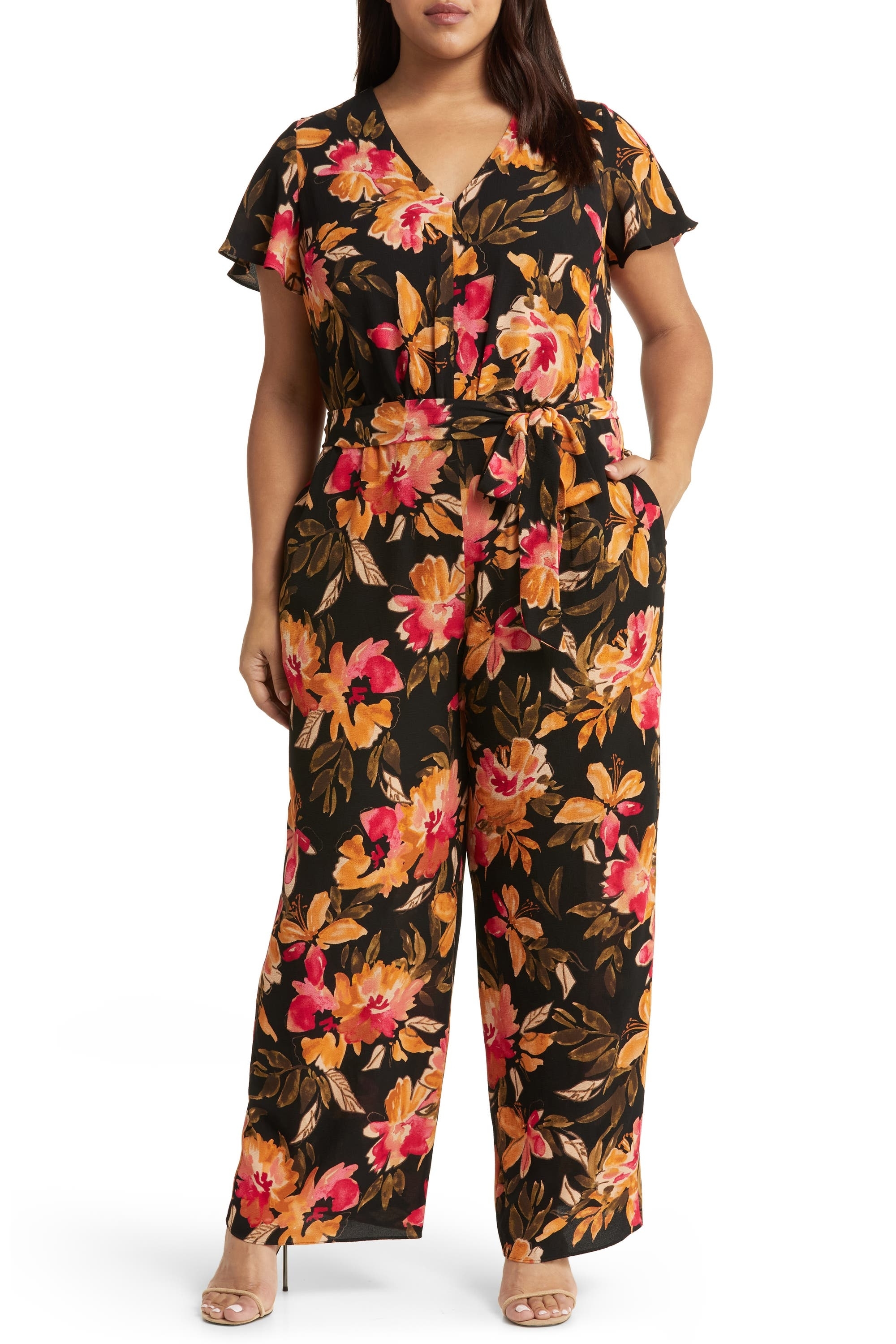 model in short sleeve long leg belted jumpsuit in a brown, orange, and pink floral pattern