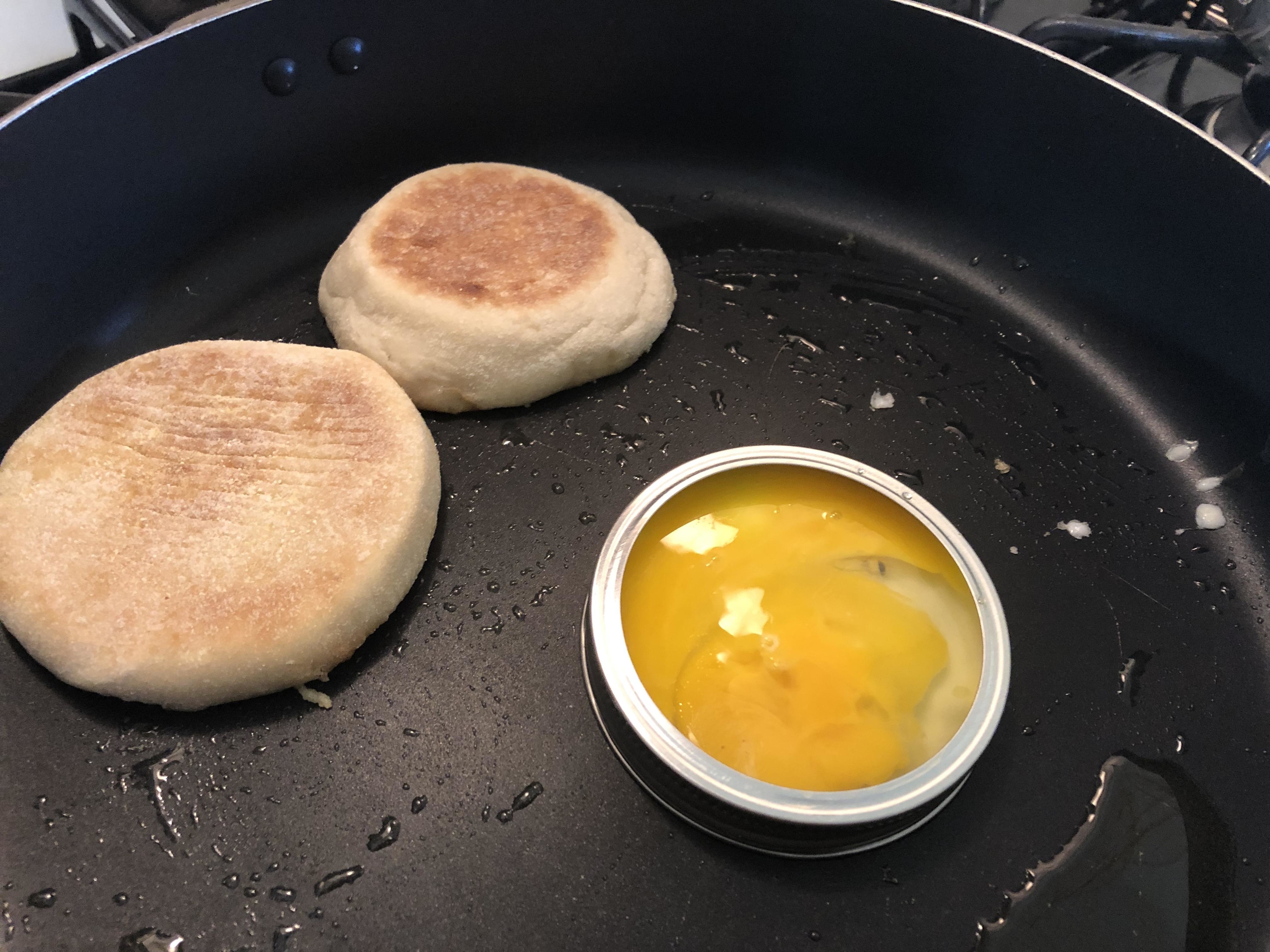 A jar lid in a skillet with an egg inside of it