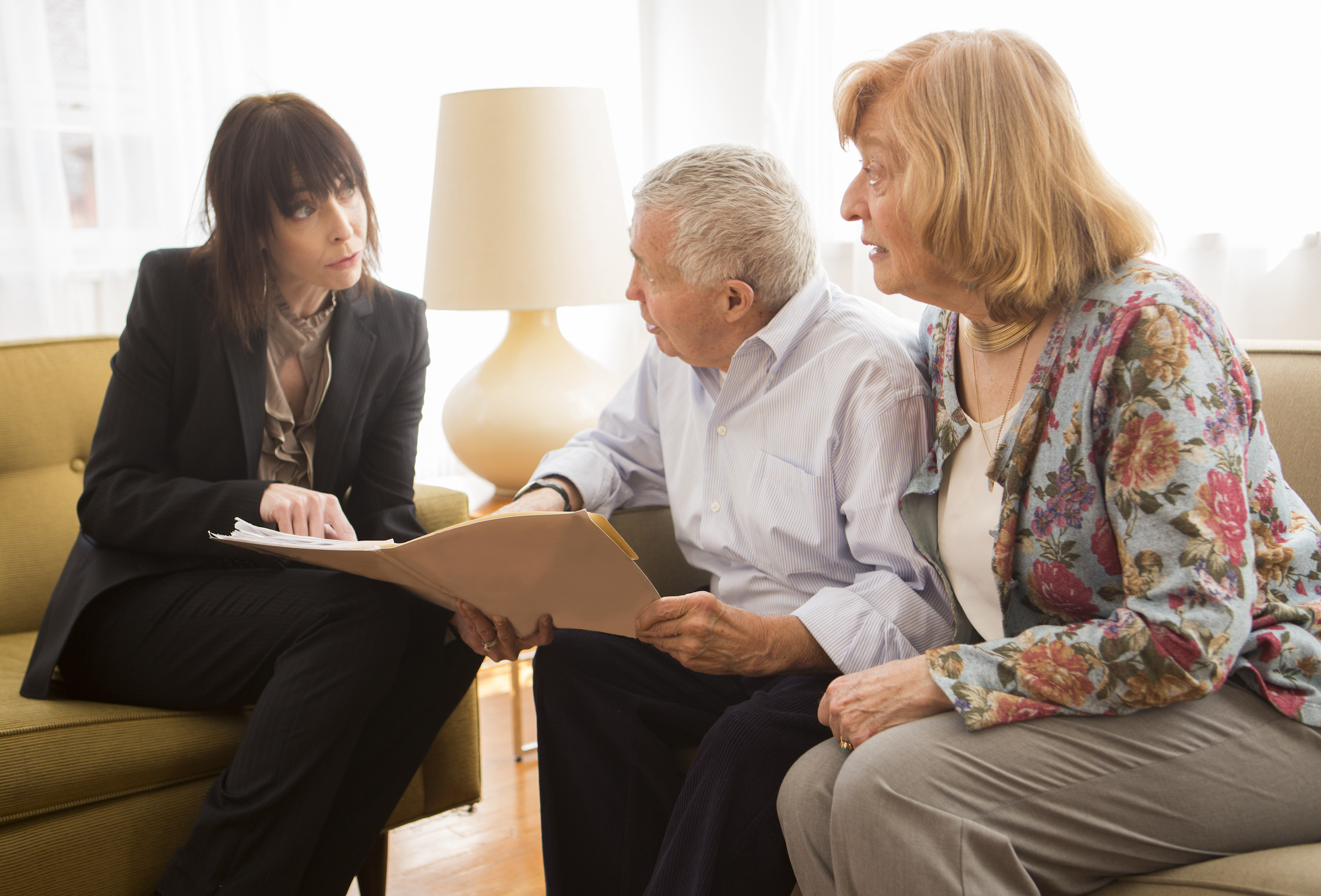 A realtor talking with an older couple and showing them a file