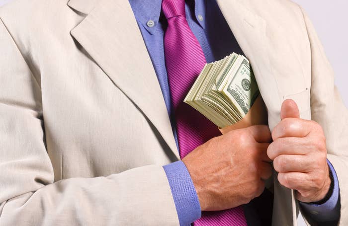 A man shoving a wad of cash in his jacket pocket