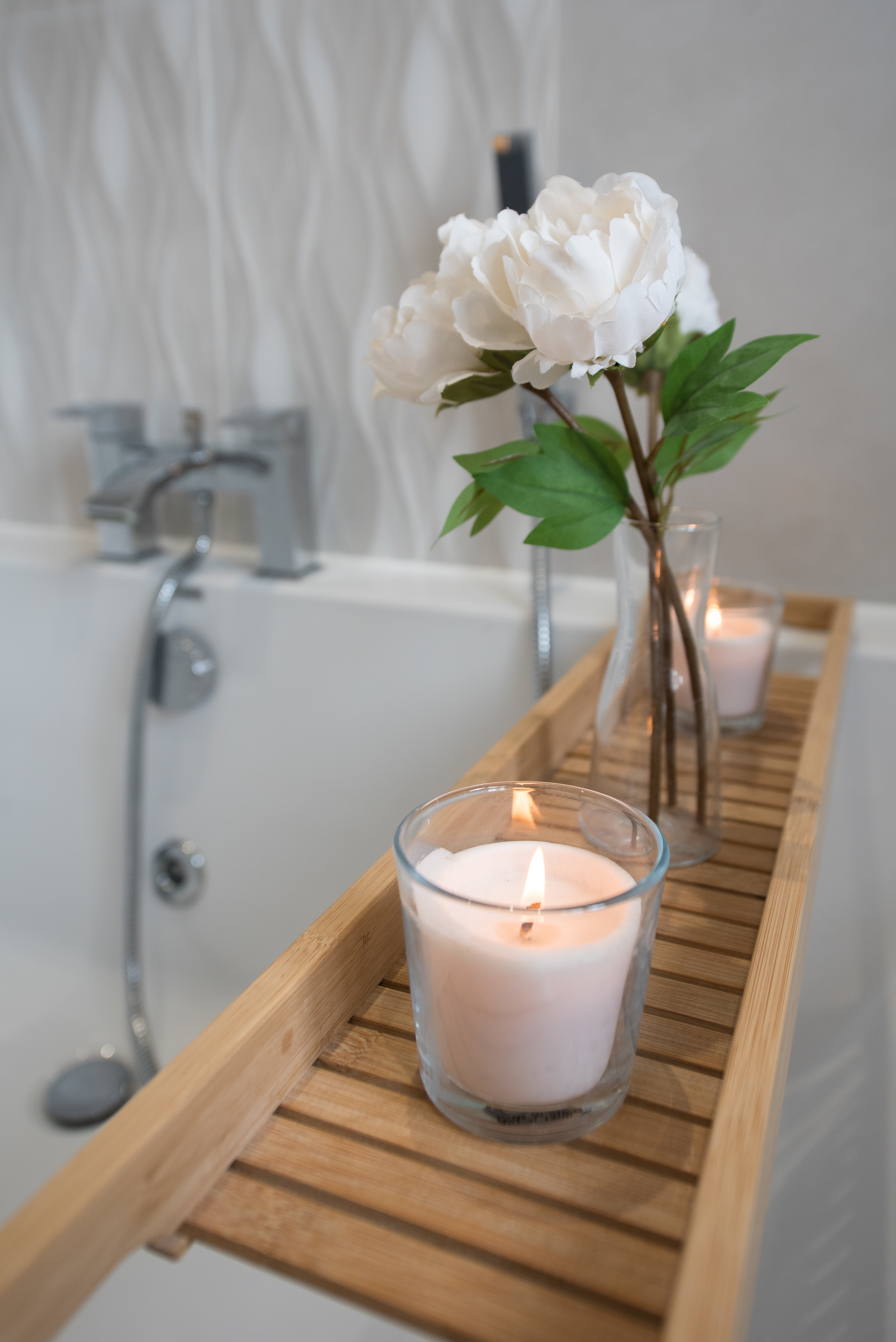 a lit candle on a tray in a bathtub