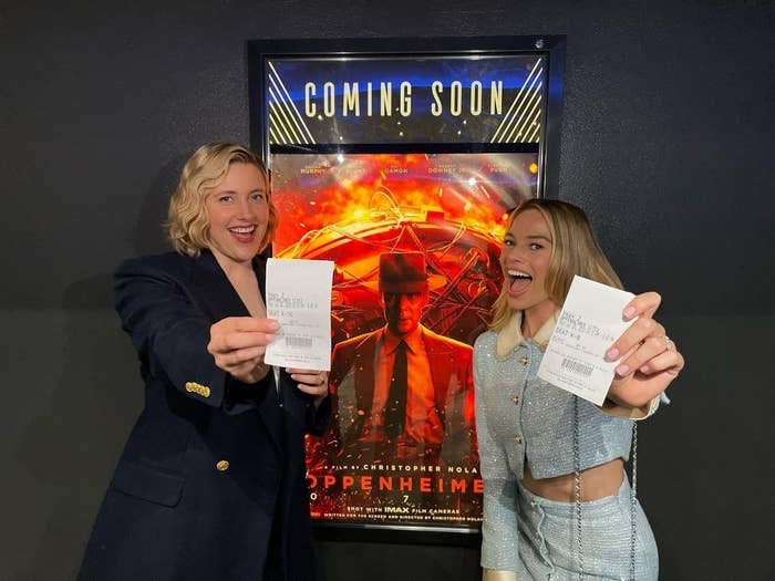 Greta and Margot holding their tickets at the theater in front of an Oppenheimer movie poster
