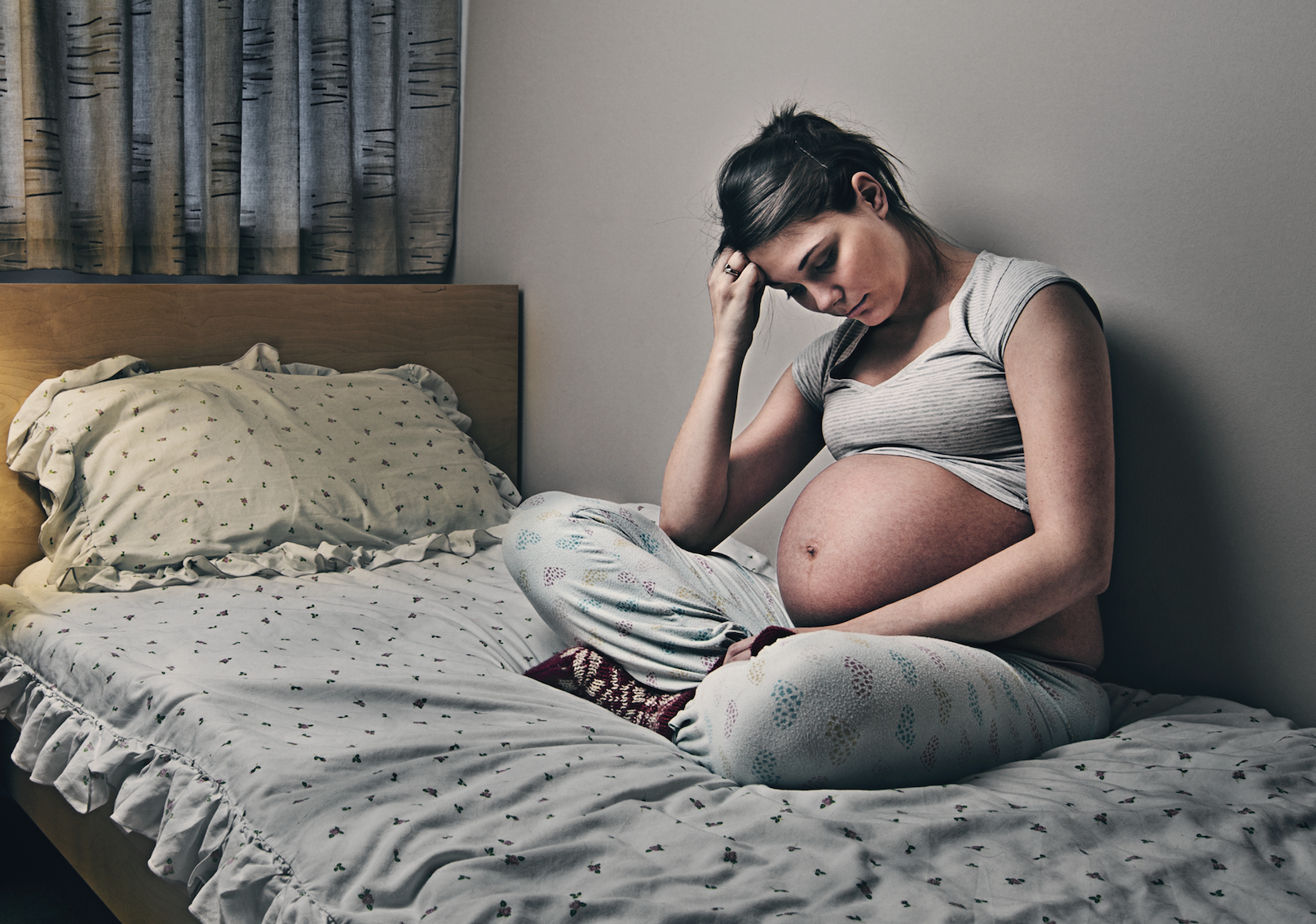 Young woman who is pregnant sitting alone in bed