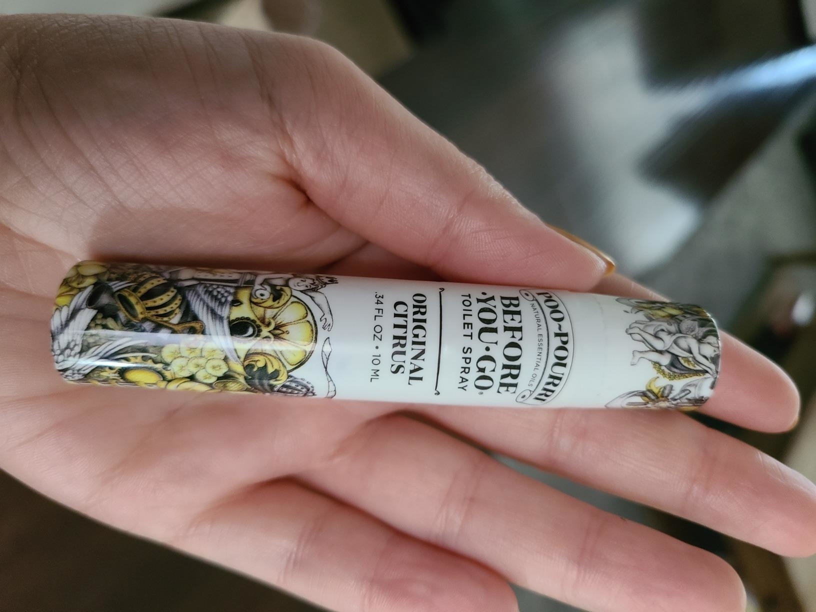 Reviewer&#x27;s photo of their hand holding the Poo-Pourri spray